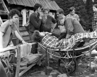 Sierpień'73. Ewka po wypadku. Była poraniona, ale ćmika nie mogła sobie odmówić. Od lewej: Marylka, goprowiec, Jacek Frejlak w kłębach ewkowego dymu, 2 x goprowiec, Janek Lulek, Kulka. Żeby panowie goprowcy się nie zmęczyli pomogliśmy im zwieźć Ewkę na Palenicę. Pomysł średni. Po tych schodach łatwiej byłoby ją znieść na plecach. Ewa jest lżejsza niż ten wózek.